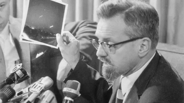J. Allen Hynek holds photo of UFO but tells press it's the moon and venus