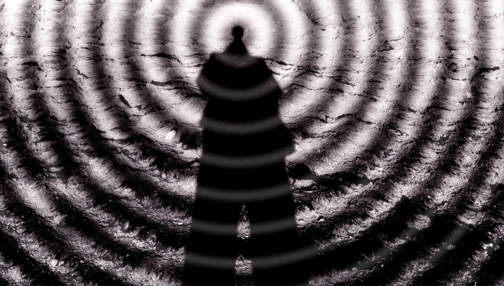 Artistic rendition of man's shadow standing in a hypnotic wheel