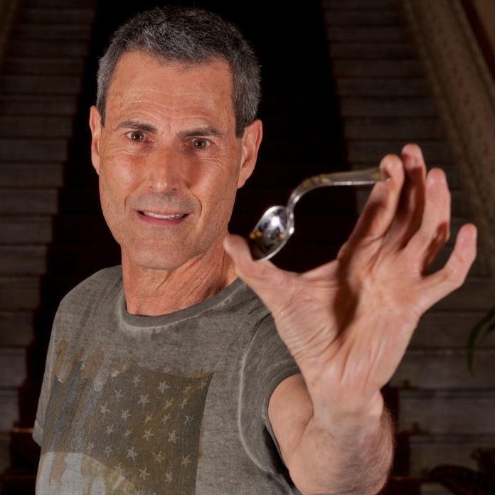 Uri Geller holding a spoon he bent