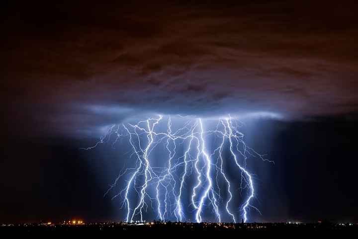 Thunderstorm with lightning strikes over a city at night