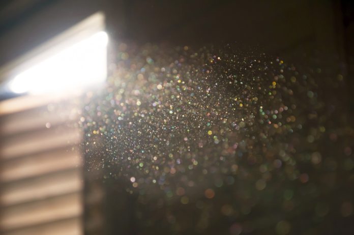 Colorful specs of dust from a stream of light entering through a window in a darkened room
